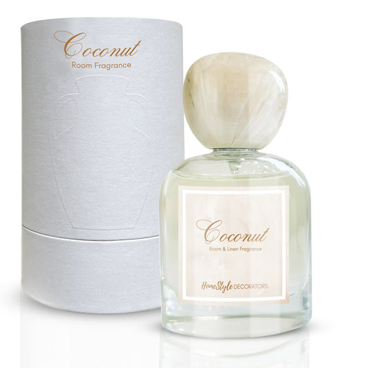 A bottle of 'Coconut' room and linen fragrance by Homestyle Decorators, accompanied by its white cylindrical packaging box, with a label and a marble top cap.